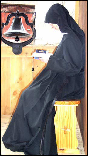 monk reading scripture while 
	waiting to ring a bell